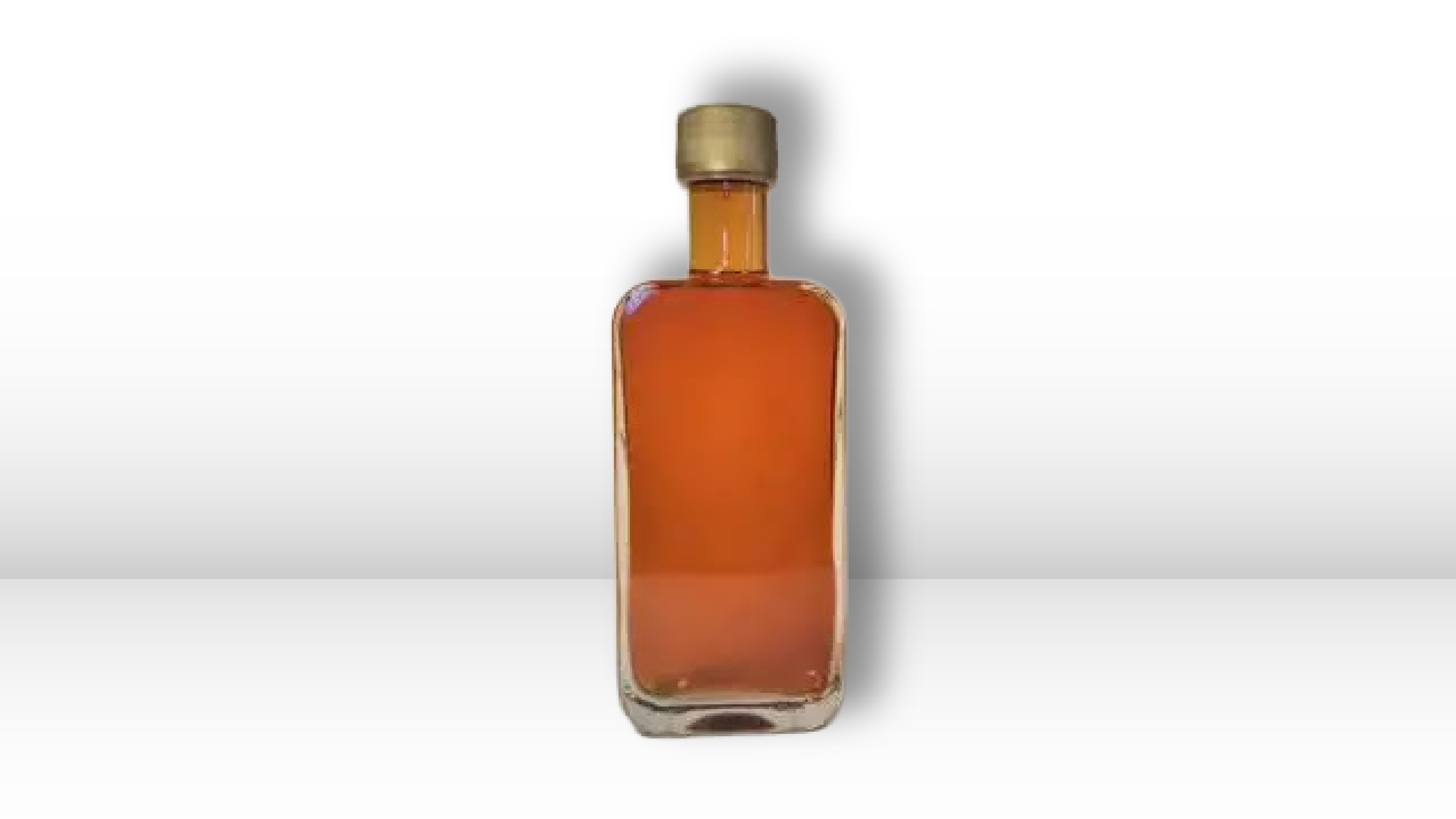 A glass bottle of maple syrup on a plain white background