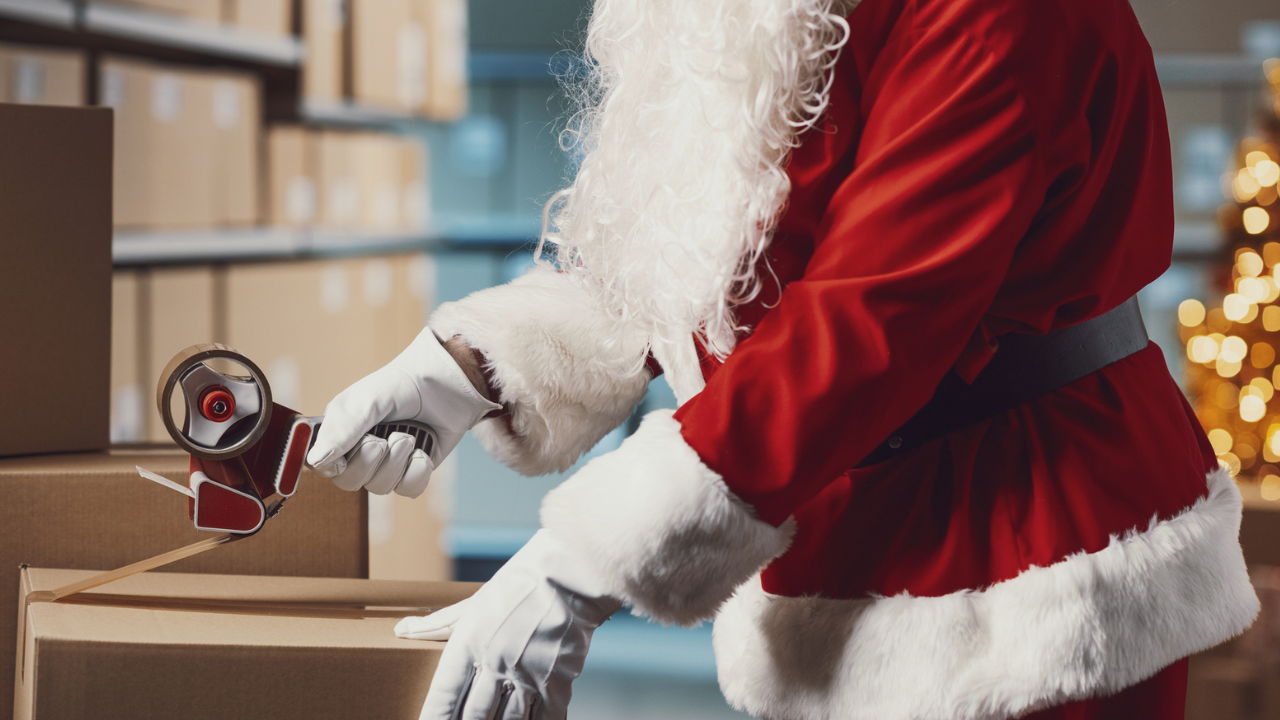 Santa securing a shipping box with palcing tape.