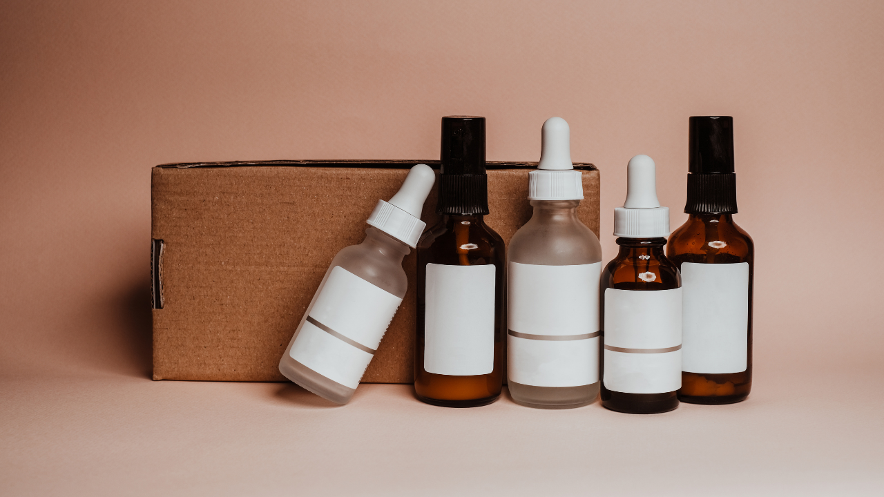 Four blank cosmetic bottles and droppers in front of a brown box